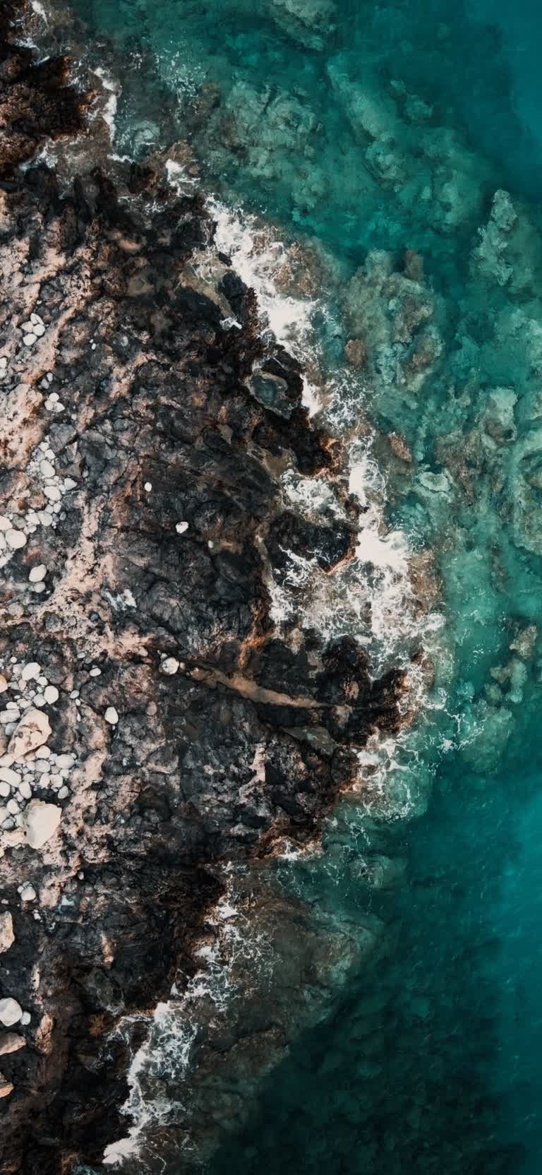 一艘船在岩石海岸附近水中的鸟瞰图