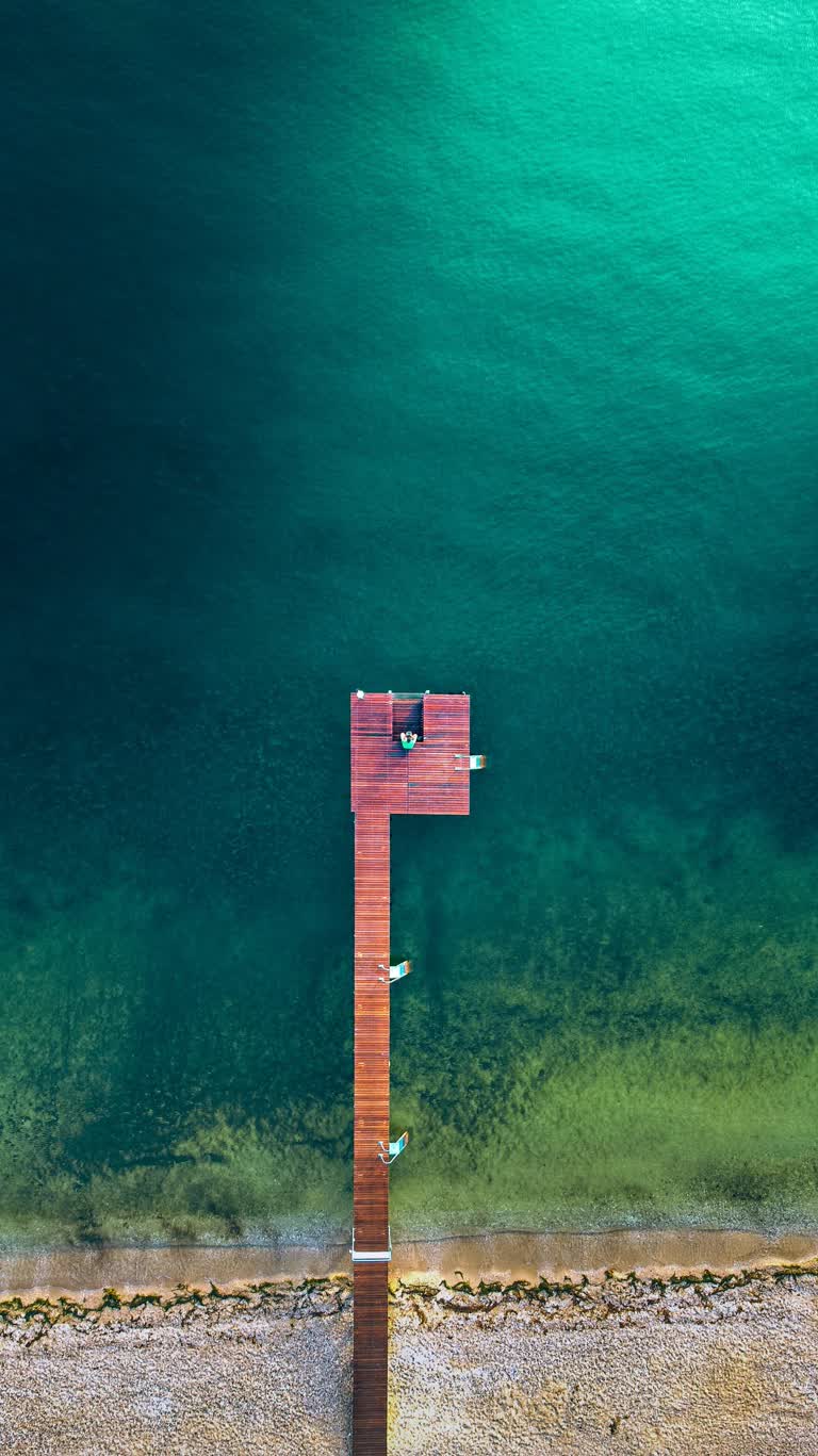 一个人坐在海边码头上的鸟瞰图