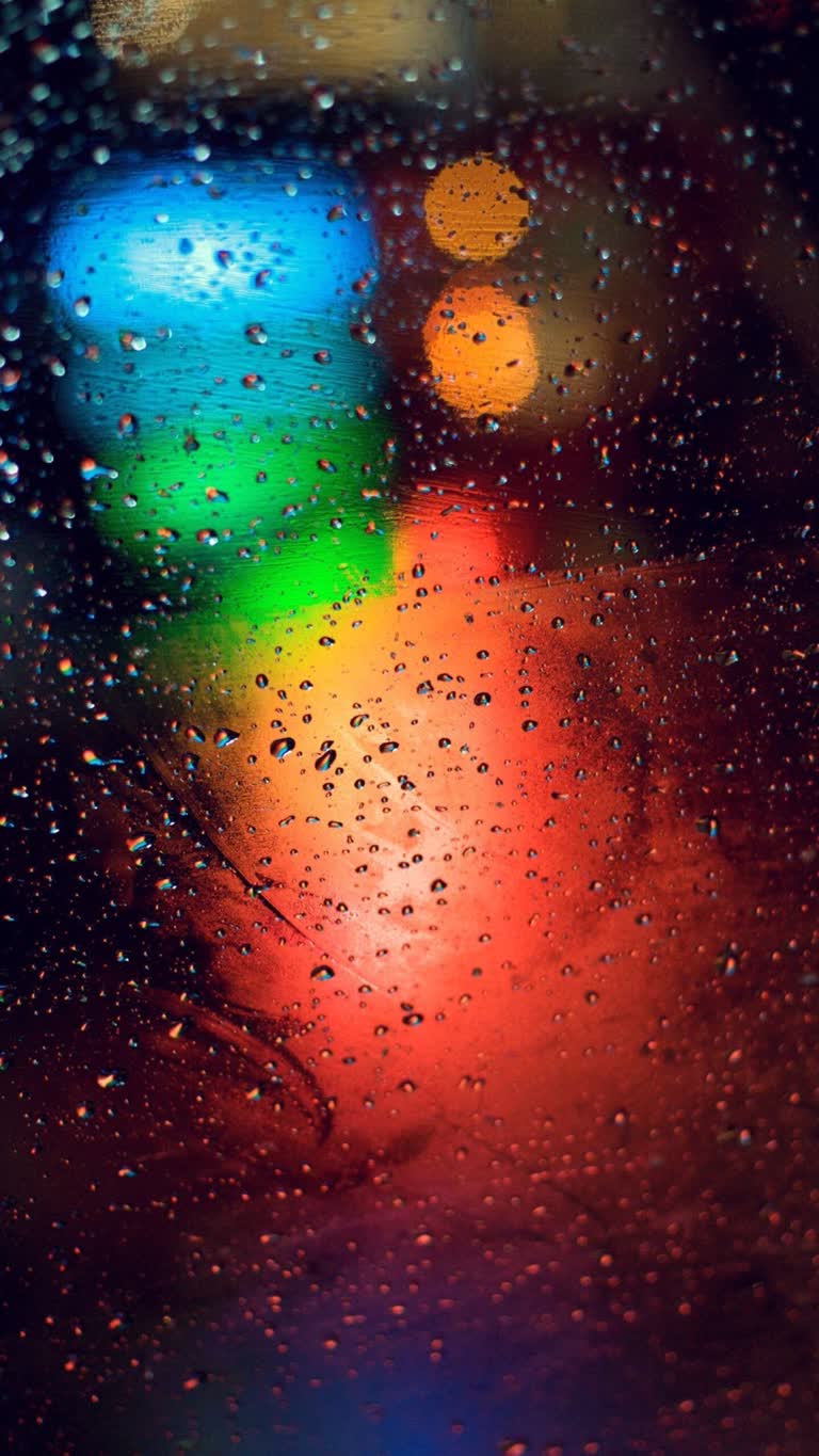 有一张模糊的路灯图像透过雨水覆盖的窗户
