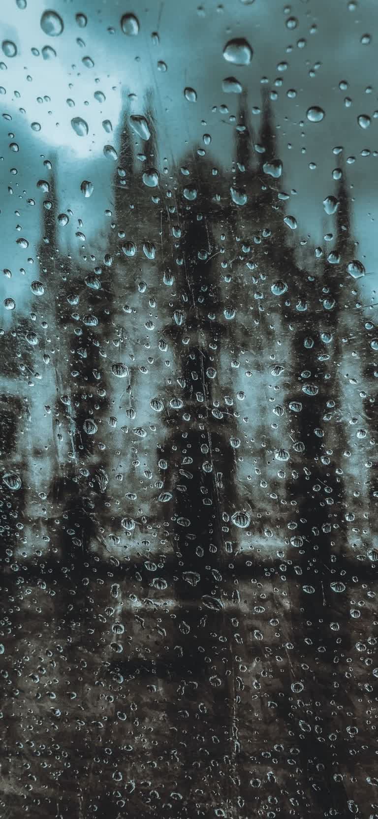 透过雨水覆盖的窗户,有一张模糊的建筑照片