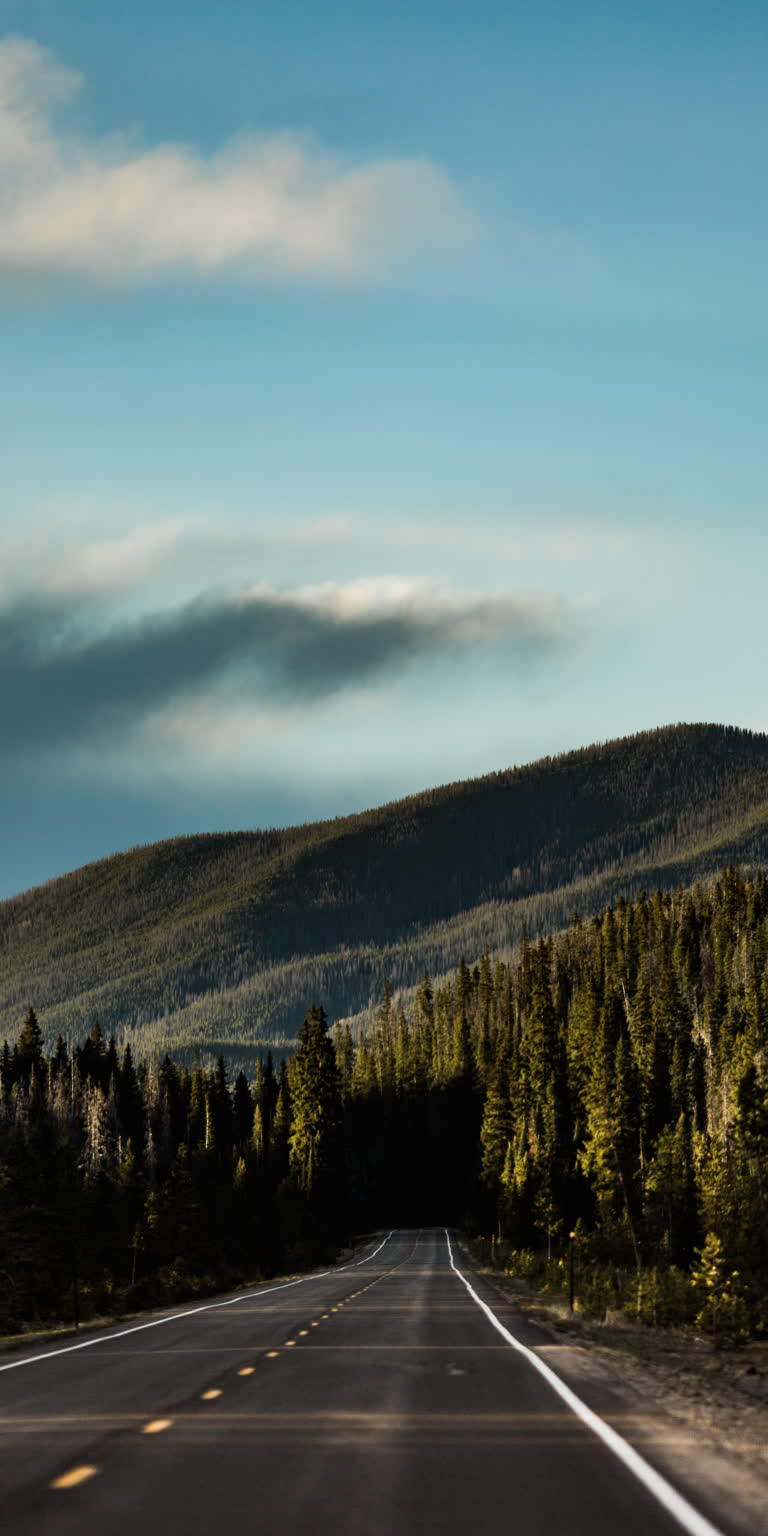 有一辆汽车在路上行驶,背景是一座山
