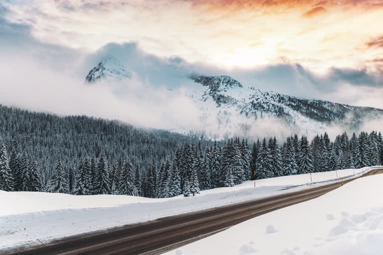 有一辆车在山里的雪路上行驶