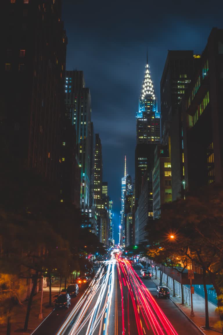 汽车在夜间在城市街道上行驶,背景是摩天大楼
