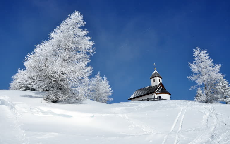 雪山上有一座教堂,背景是树木