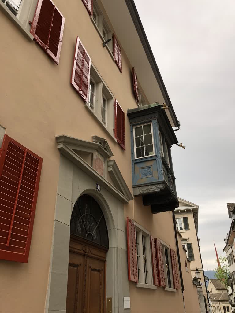 一栋建筑物的一侧有一个带有红色百叶窗的时钟