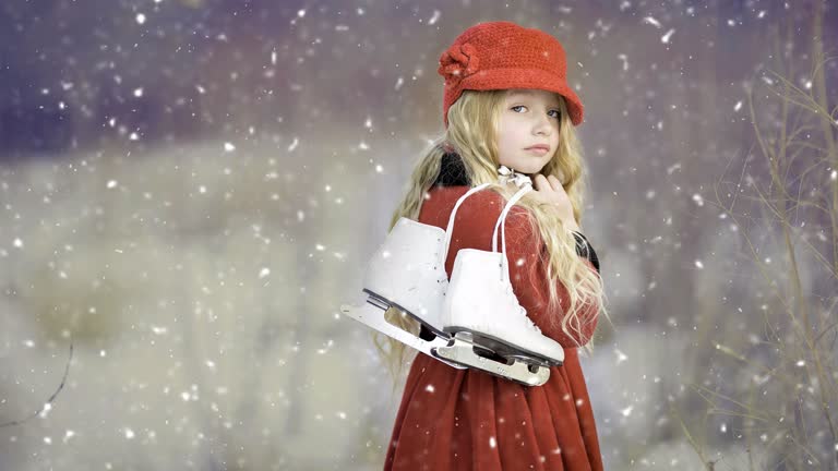 有一个小女孩,拿着溜冰鞋站在雪地里