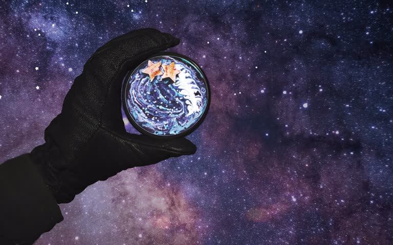 有一只手拿着一个玻璃杯,里面有一颗行星