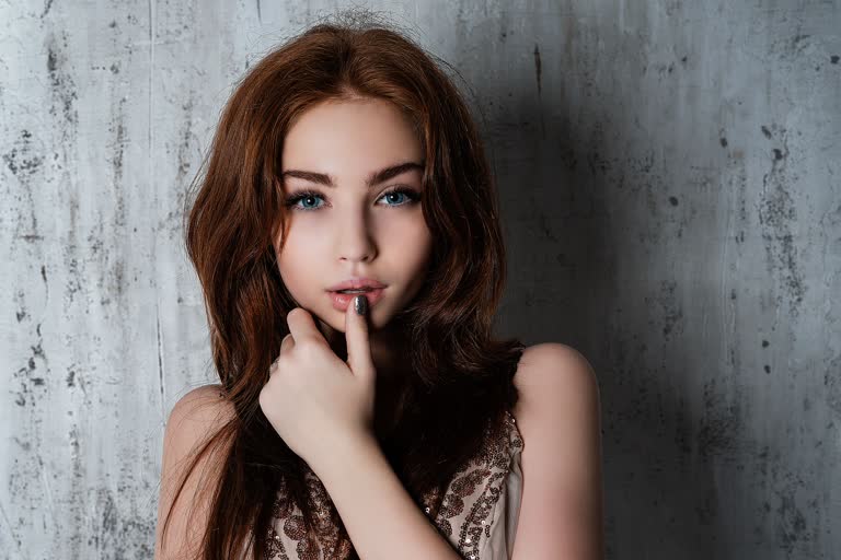 这是一个女人用手指放在嘴唇上摆姿势的图片