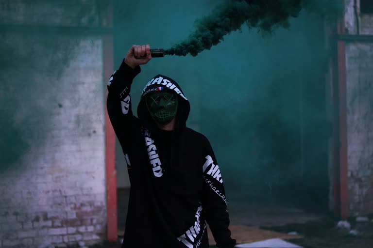 有一个穿着黑色连帽衫的男人拿着一根绿色的烟棒