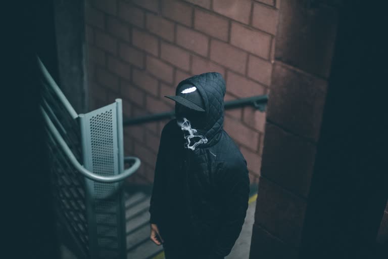 有一个穿着黑色连帽衫的男人走下楼梯