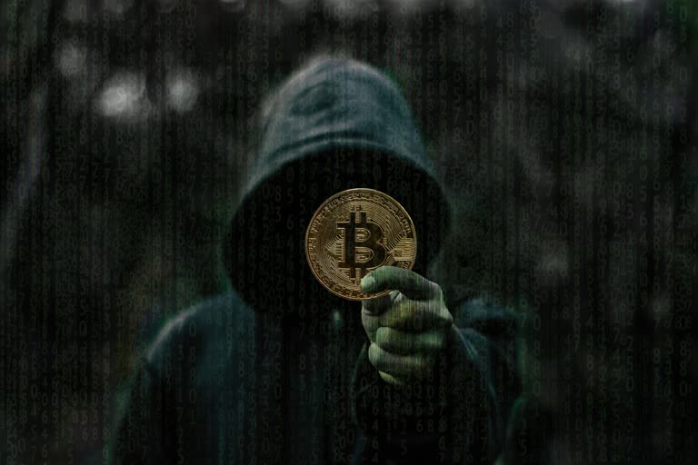 有一个穿着连帽衫的男人拿着一枚比特币