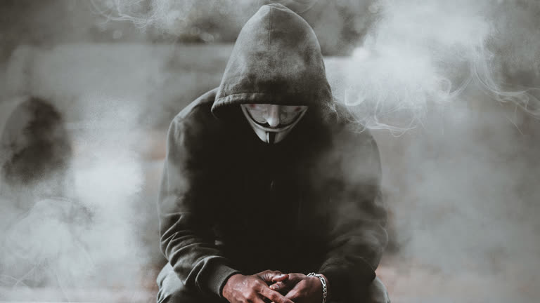 有一个穿着连帽衫的男人坐在一个烟雾缭绕的房间里