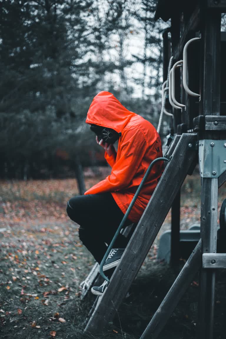 梯子上坐着一个穿着橙色连帽衫的男人