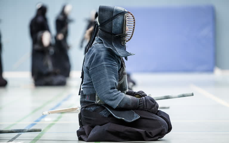 有一个男人坐在地板上,手里拿着剑