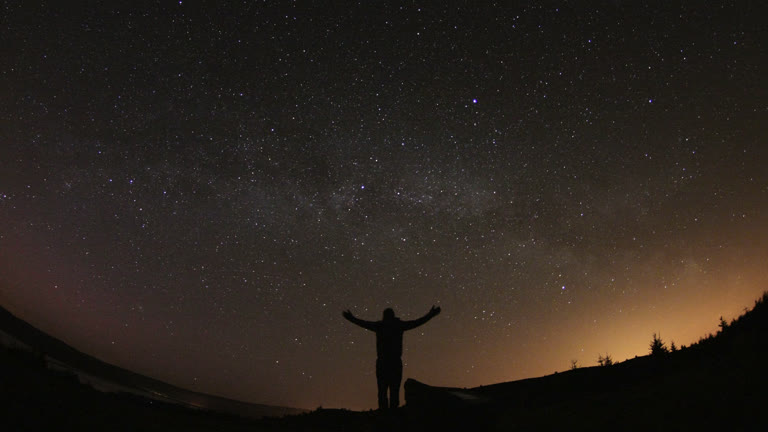 有一个人站在星空下的山丘上
