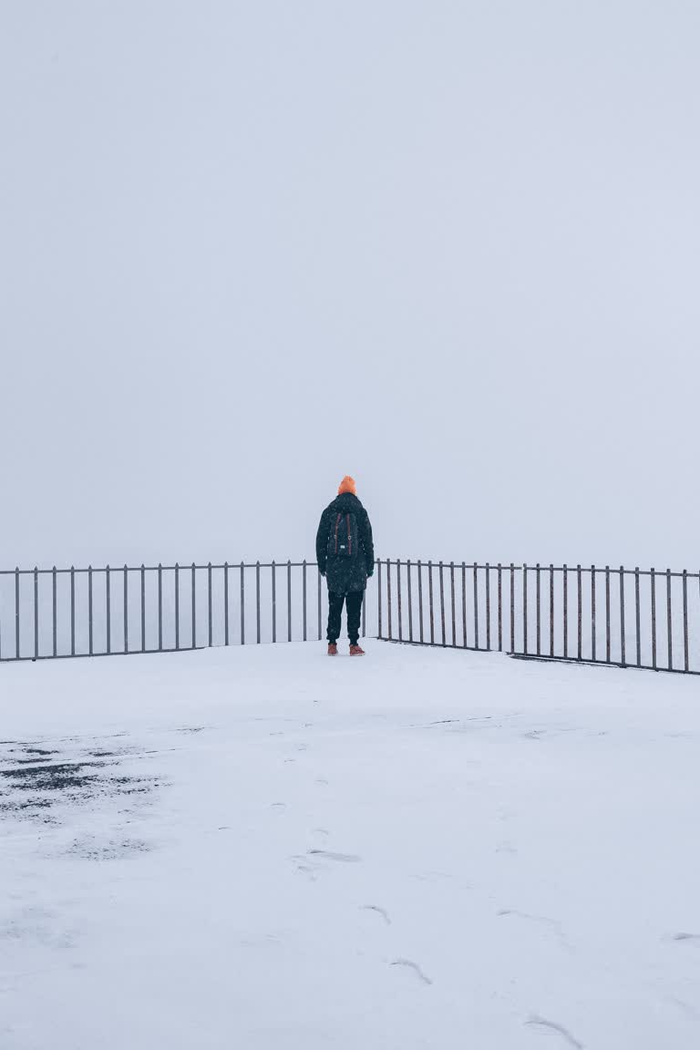 有一个人站在篱笆附近的雪地里