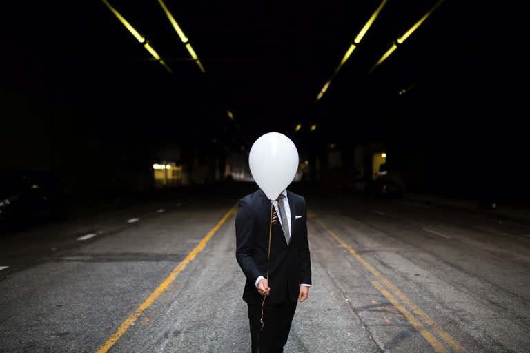 有一个西装打领带的男人,头上戴着一个气球