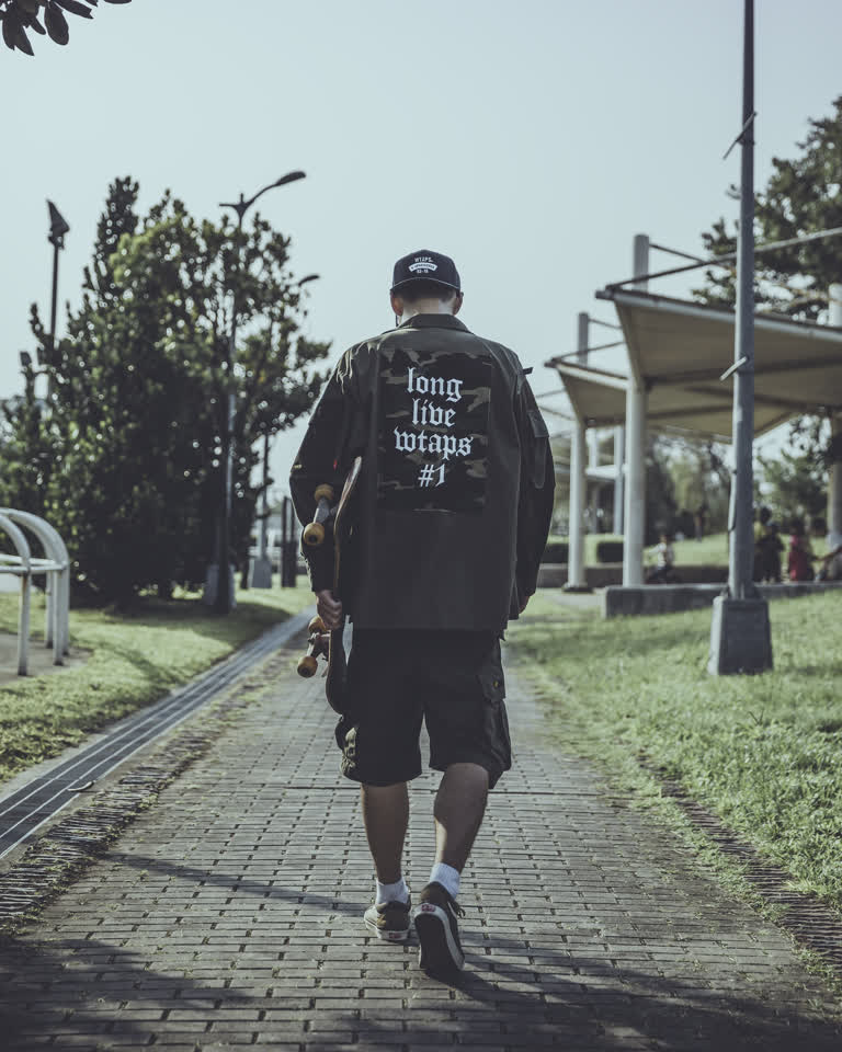有一个男人,他正拽着滑板走在街上