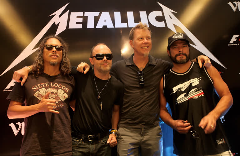 三个男人并排站在 Metallicica 标志前