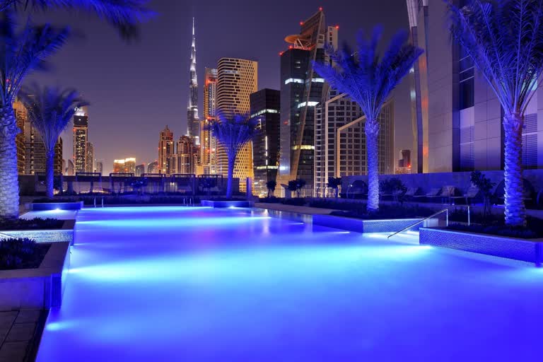 游泳池的夜景,背景是棕榈树和摩天大楼