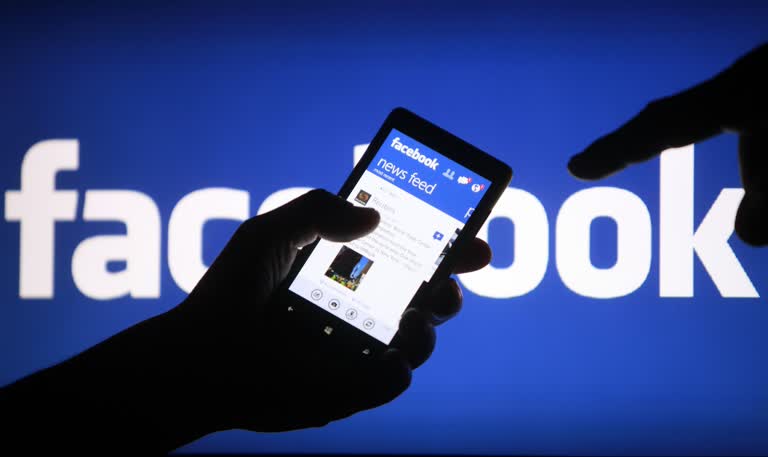 有一个人在 Facebook 标志前拿着手机