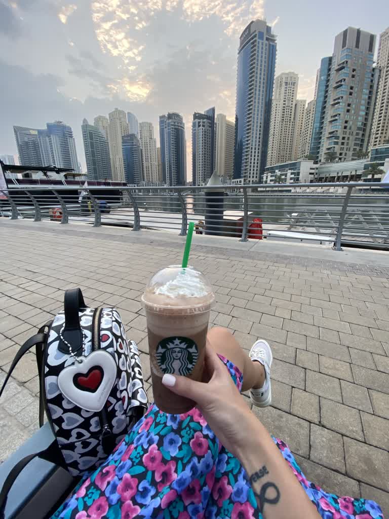 有一个人坐在长凳上,手里拿着一杯咖啡