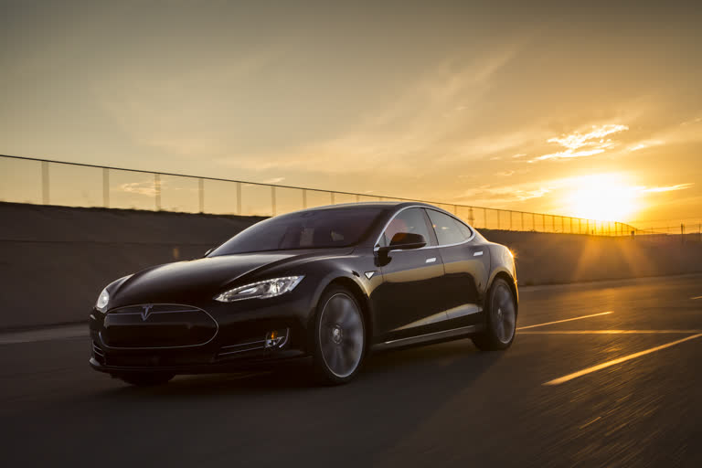 这是一辆黑色特斯拉 Model S 在路上行驶的照片