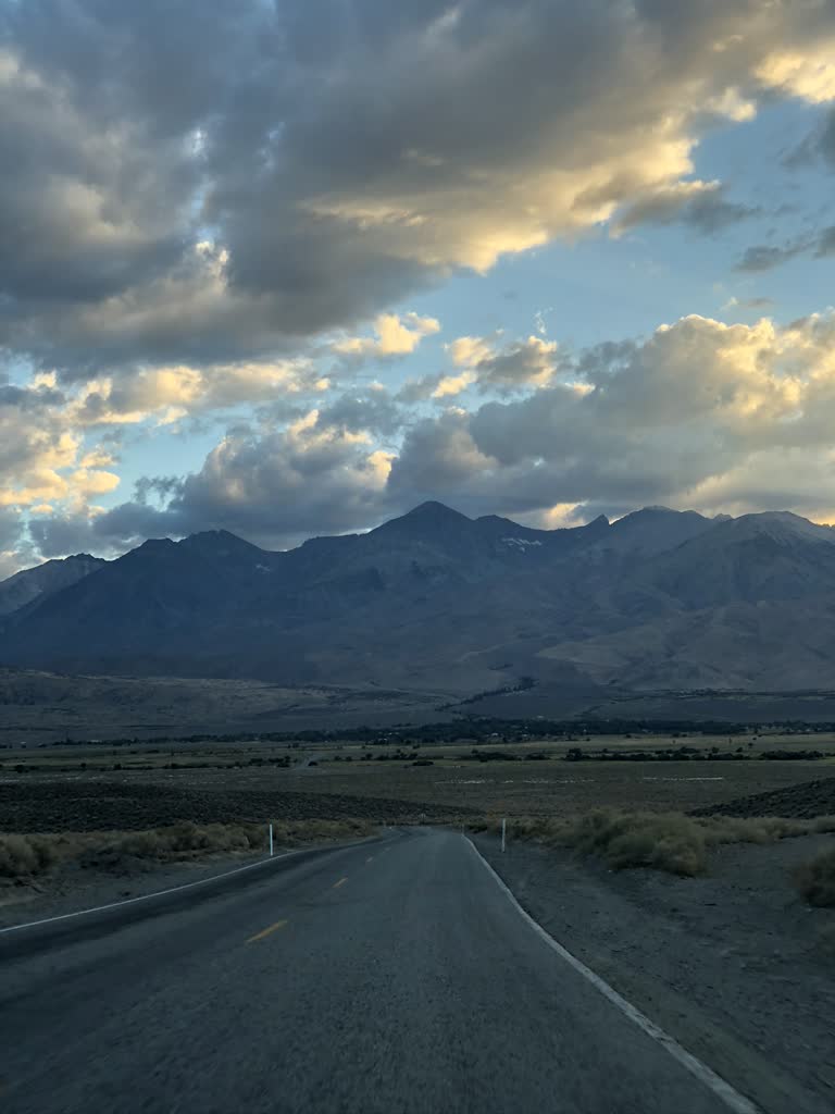 有一条穿过沙漠的路,背景是群山