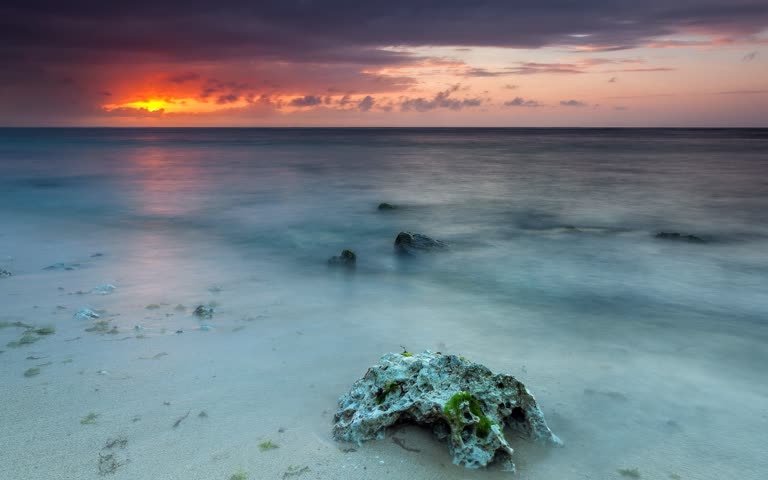 海滩上有一块岩石,背景是日落