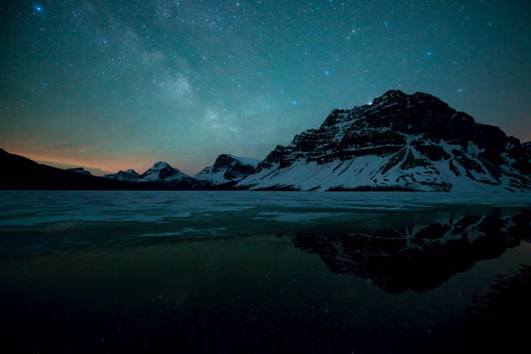 结冰的湖面上繁星点点的夜空,背景是群山