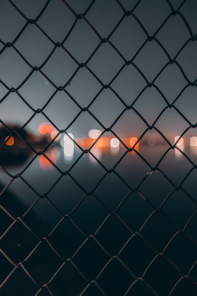 晚上透过铁丝网围栏可以看到城市