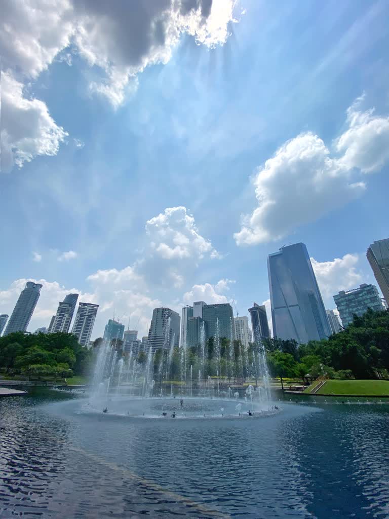 池塘中间有一个喷泉,背景是建筑物