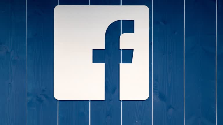 蓝色木镶板墙上有一个白色的 Facebook 标志