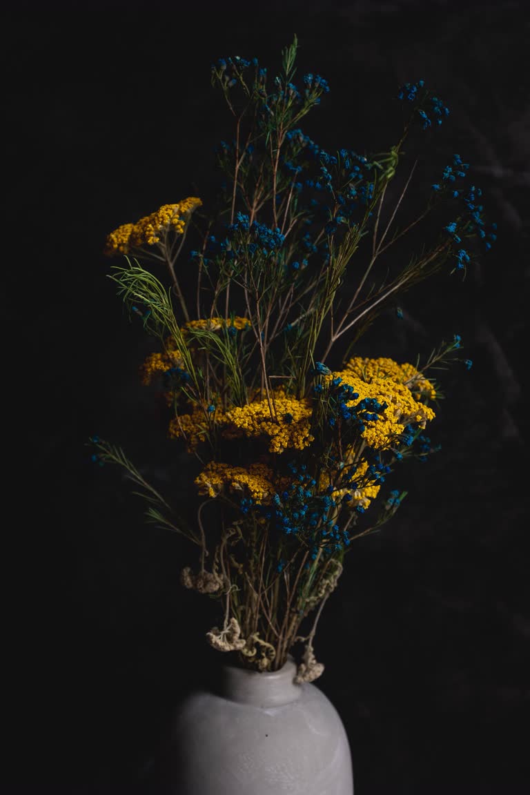 有一个白色的花瓶,里面有黄色和蓝色的花朵