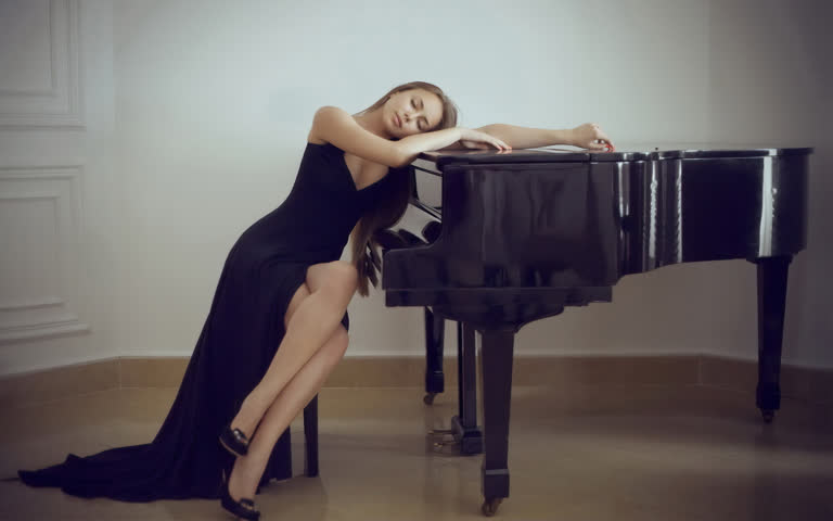 有一个穿着黑色长裙的女人靠在钢琴上