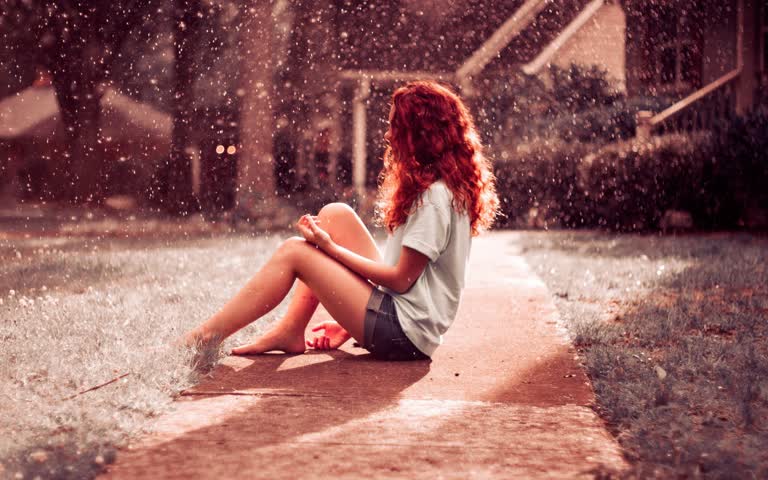 有一个女人,在雨中坐在人行道上