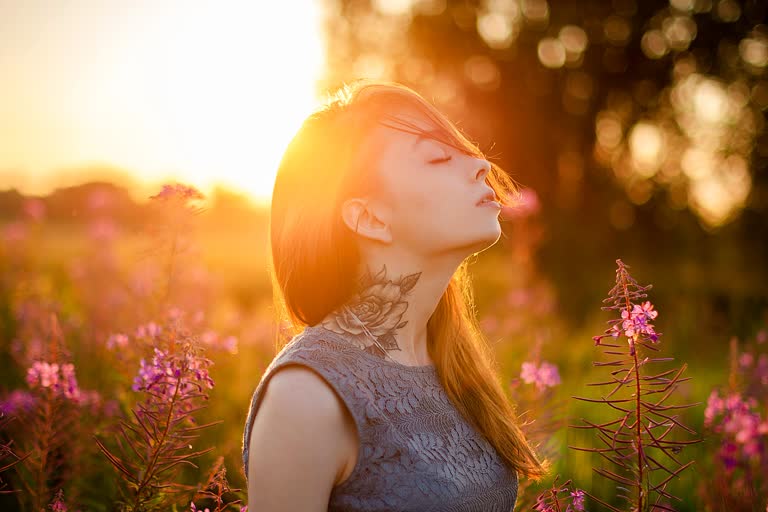 有一个女人闭着眼睛站在花田里
