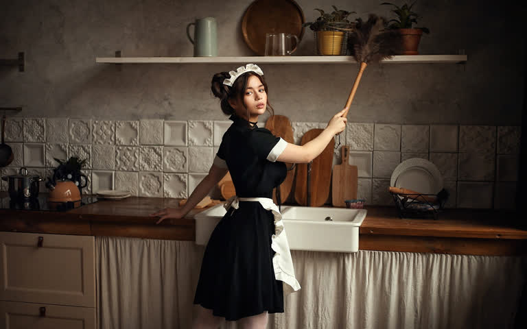有一个女人拿着扫帚站在厨房里