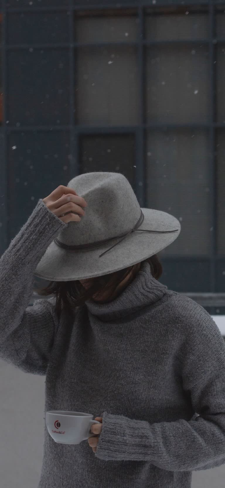 有一个女人戴着帽子,手里拿着一杯咖啡