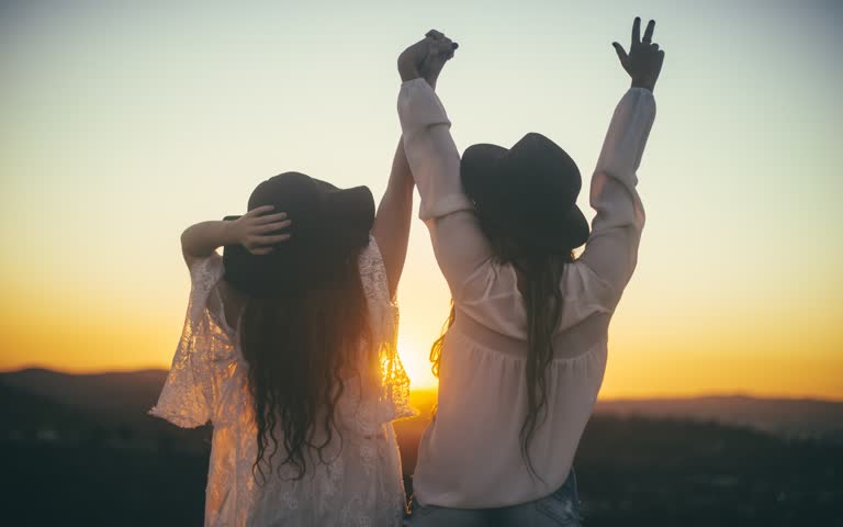 有两个女人双手举在空中站起来